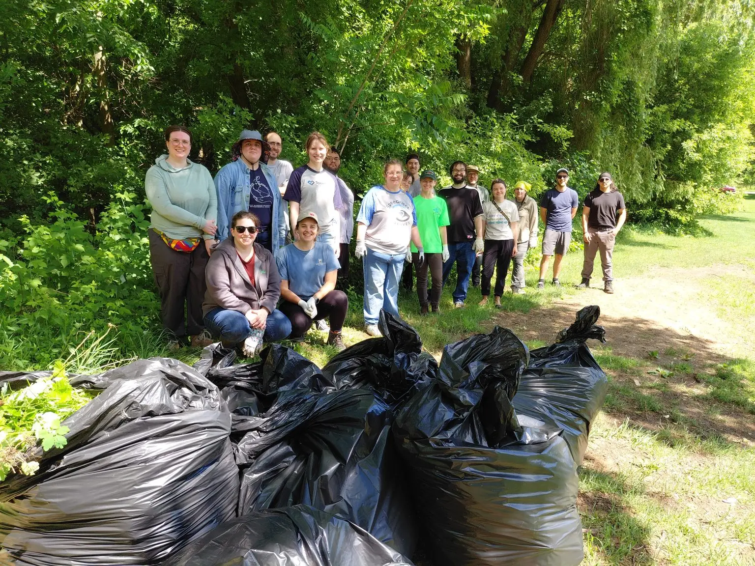 group of people standing in the woods with trash bags
